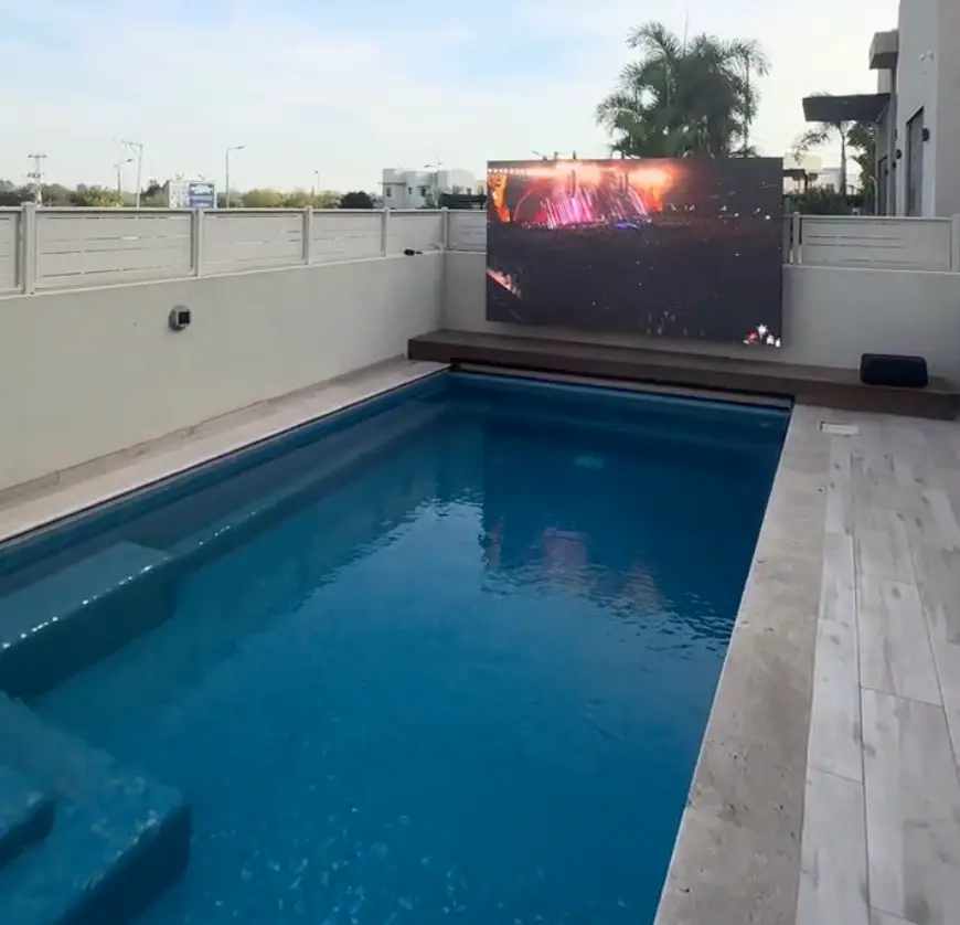 משפחה צופה במשחק כדורגל על מסך LED ליד הבריכה